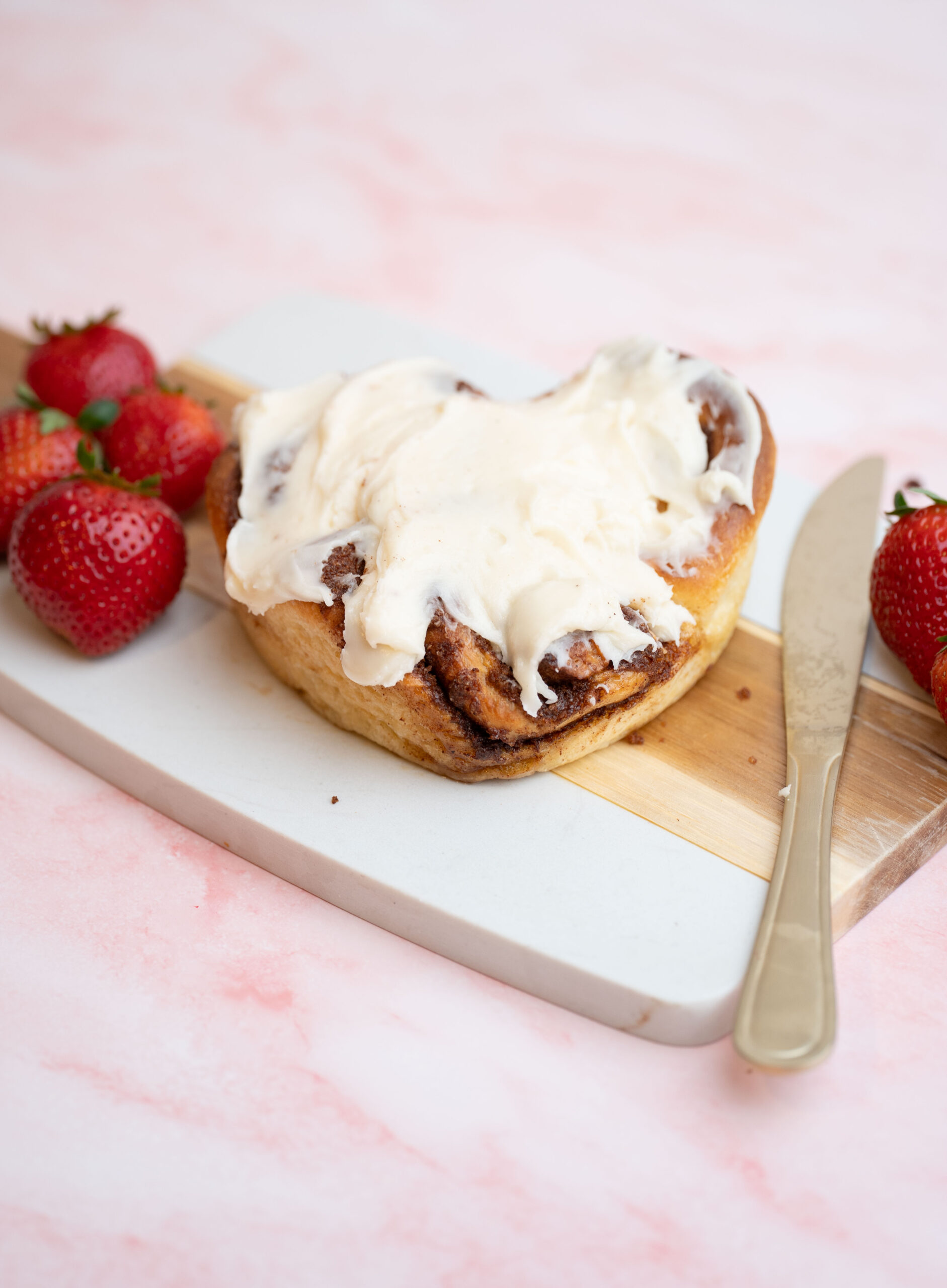 heart shaped cinnamon roll on a marble cutting board